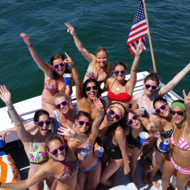 group of girls smiling and throwing hands up on back of boat