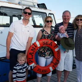 family posing for a picture on the dock next to the boat