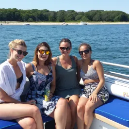 four girls smiling on the back of the boat