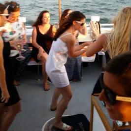 a girl dancing on the boat with people cheering around her