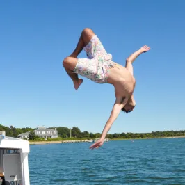 boy flipping off the side of the boat into the water