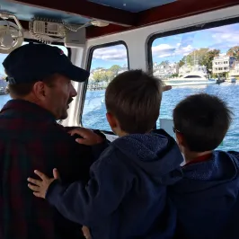 two little boys and an older man driving the boat