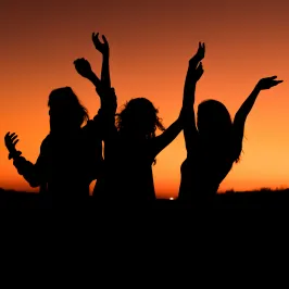 silhouette of three girls with an orange sunset in the background
