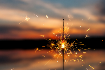 sparkler in the foreground, sunset in the background